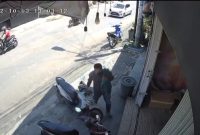 Seorang pria berperawakan gempal terpantau kamera CCTV mengambil handphone milik salah satu konsumen toko es krim yang tertinggal di dashboard motor. (FOTO Tangkap Layar Video)