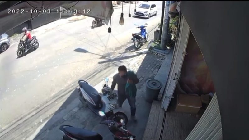 Seorang pria berperawakan gempal terpantau kamera CCTV mengambil handphone milik salah satu konsumen toko es krim yang tertinggal di dashboard motor. (FOTO Tangkap Layar Video)