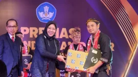 Uas Romansah saat menerima penghargaan guru Dedikatif tingkat nasional. (Istimewa)