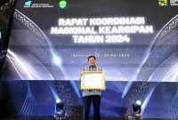 Kepala Dinas Perpustakaan dan Kearsipan (DPK) Kota Cilegon, Ismatullah saat menerima penghargaan ANRI untuk Pemkot Cilegon. (Istimewa)