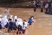 Para pelajar saat menyeberangi sungai dengan arus deras untuk berangkat dan pulang sekolah. (FOTO Tangkap Layar video)