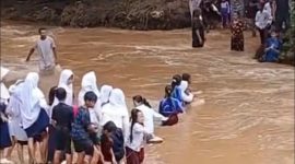 Para pelajar saat menyeberangi sungai dengan arus deras untuk berangkat dan pulang sekolah. (FOTO Tangkap Layar video)